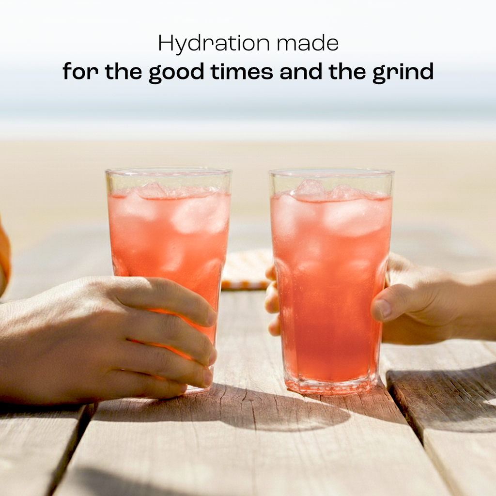 Two tall glasses of pink electrolyte drink with ice, held by hands