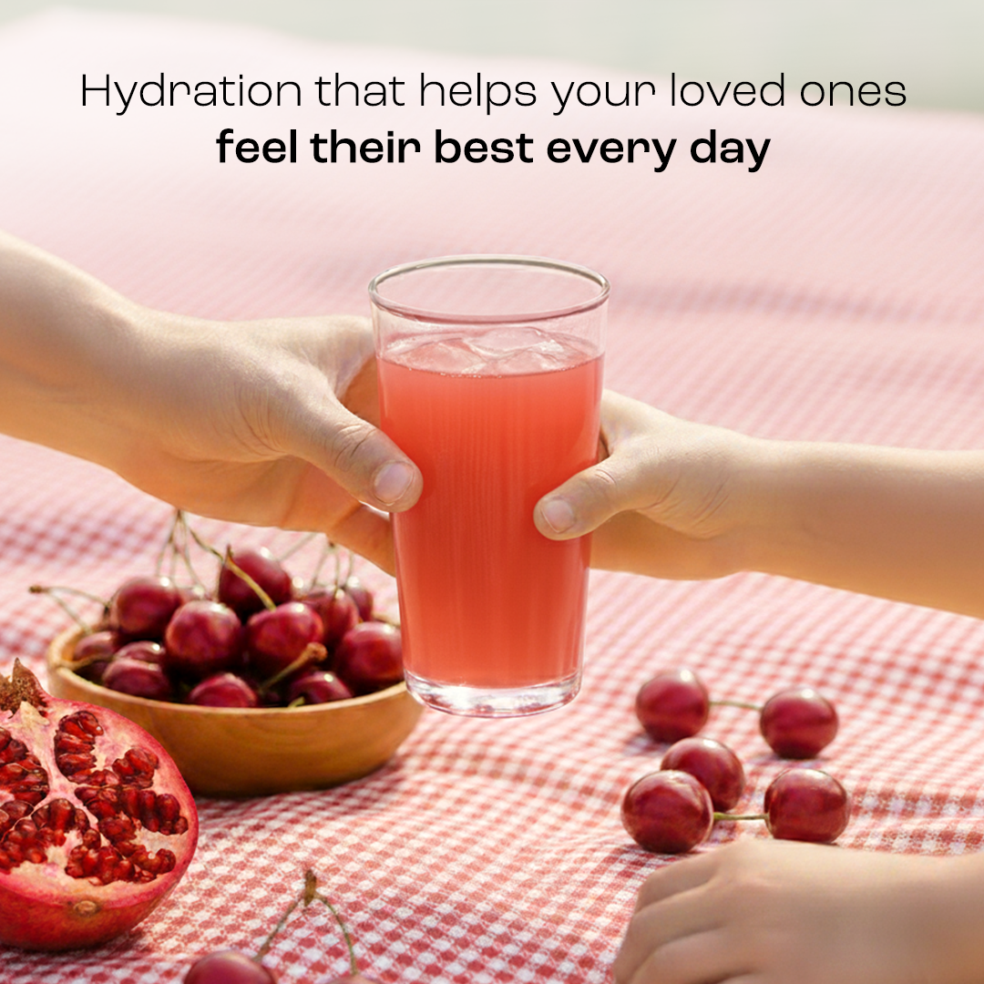 Red electrolyte drink in a glass held by hands with cherries and pomegranate