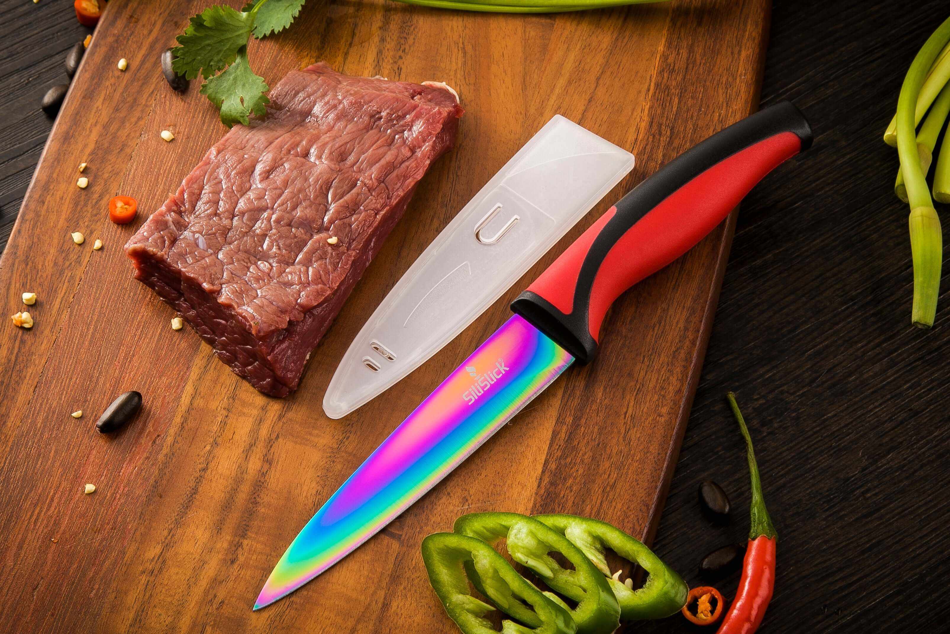 Paring knife with red handle and rainbow blade; clear blade cover shown