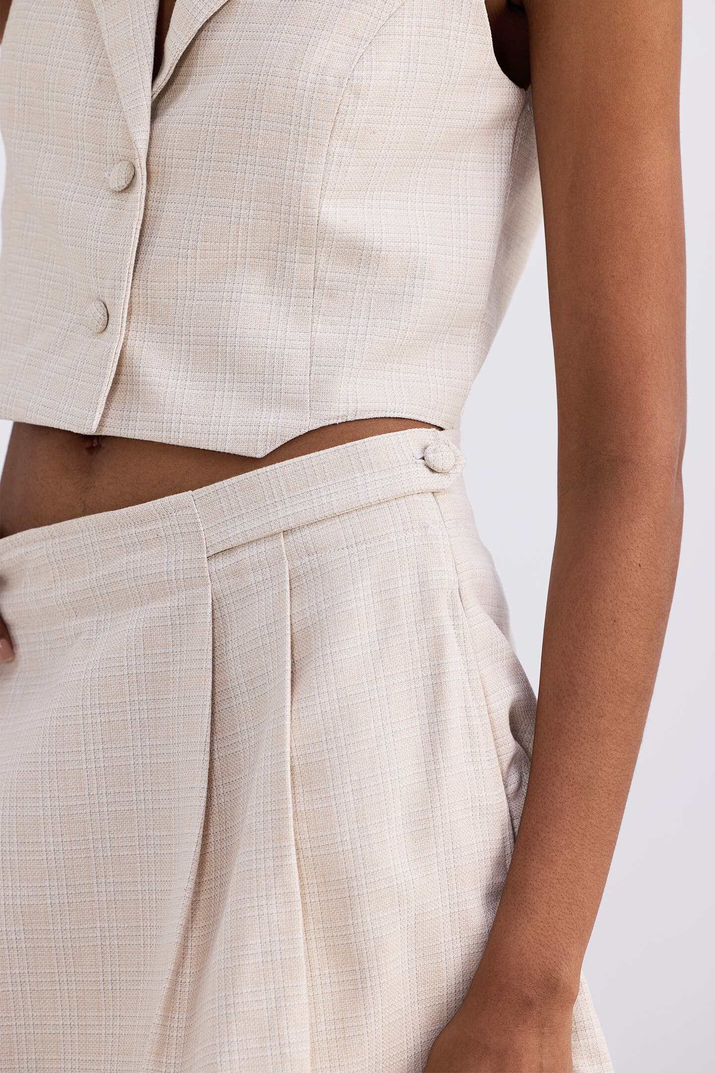 Close-up of cream cotton tweed skort: pleats, stitched waistband, and side seam