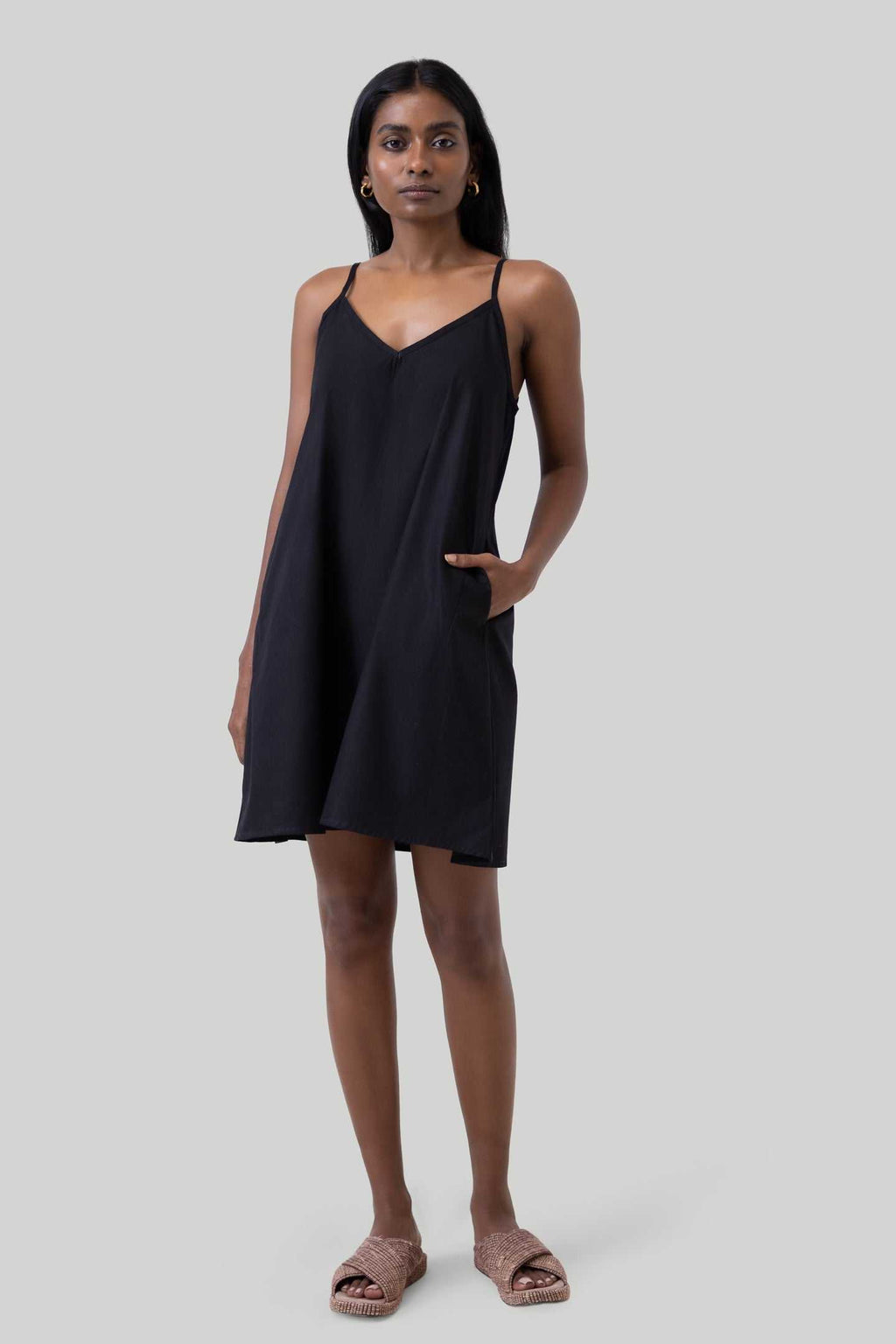 Black tent dress on model, thin spaghetti straps and straight hem above the knee