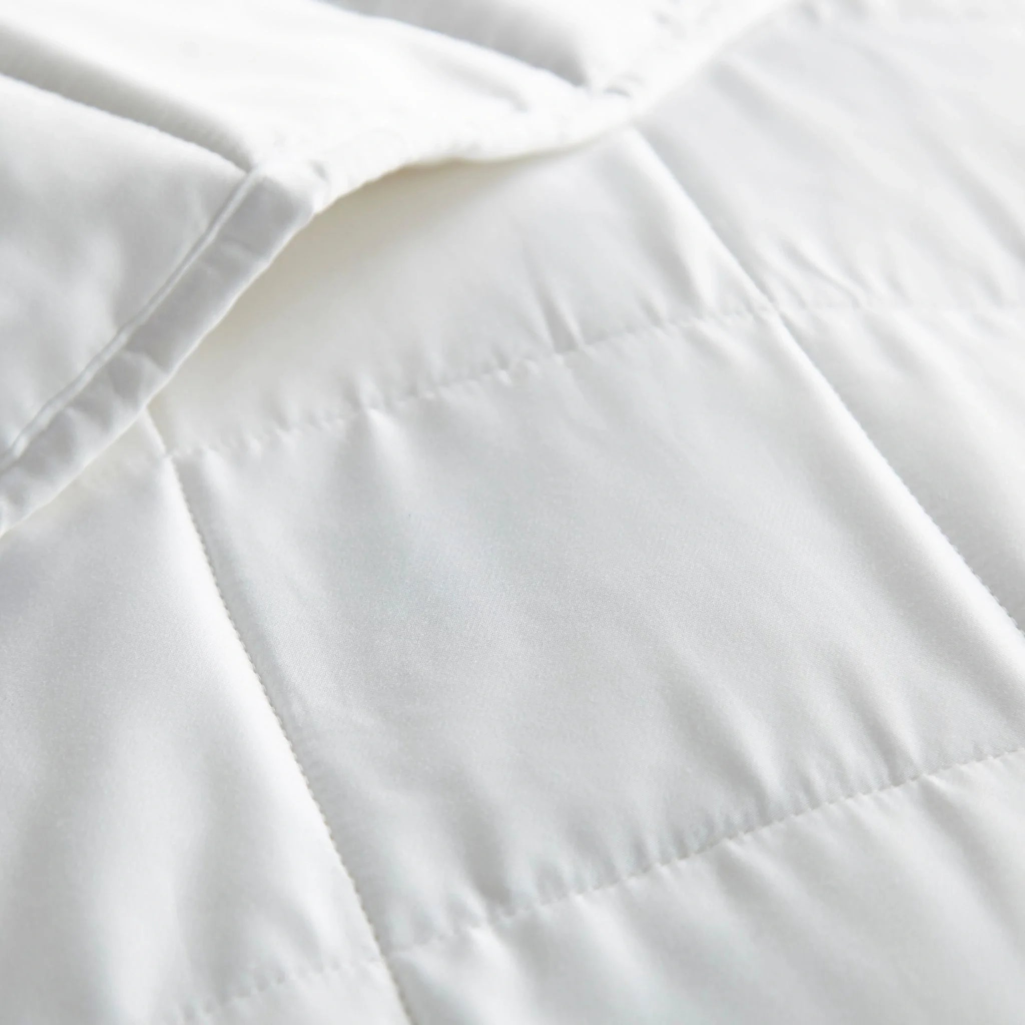 Close-up of white comforter fabric with stitched seam lines