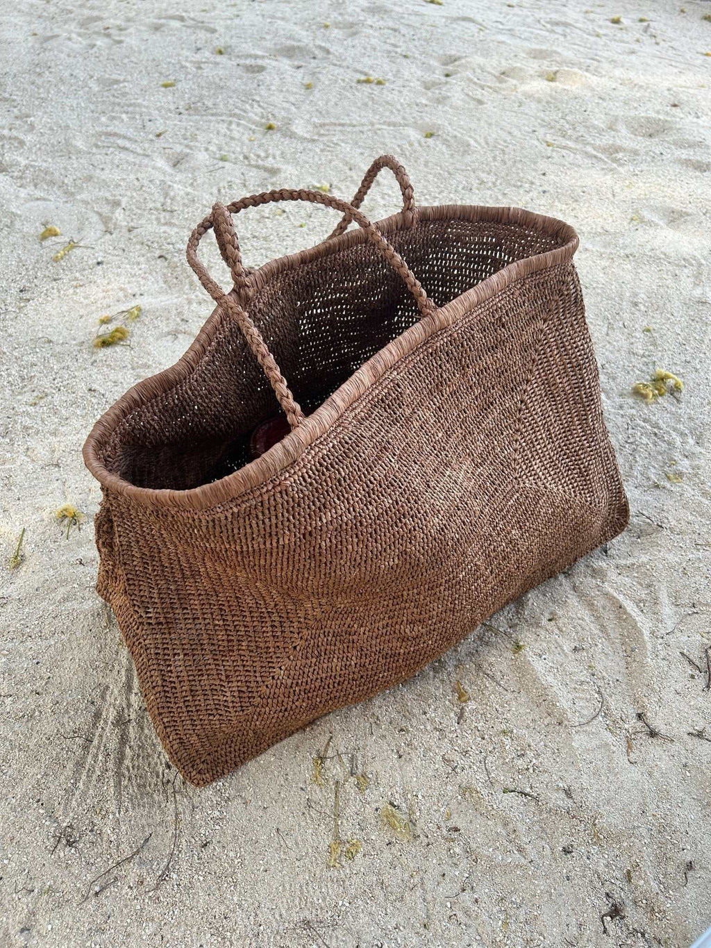 Caramel brown woven raffia tote bag with twin rope handles and roomy shape.