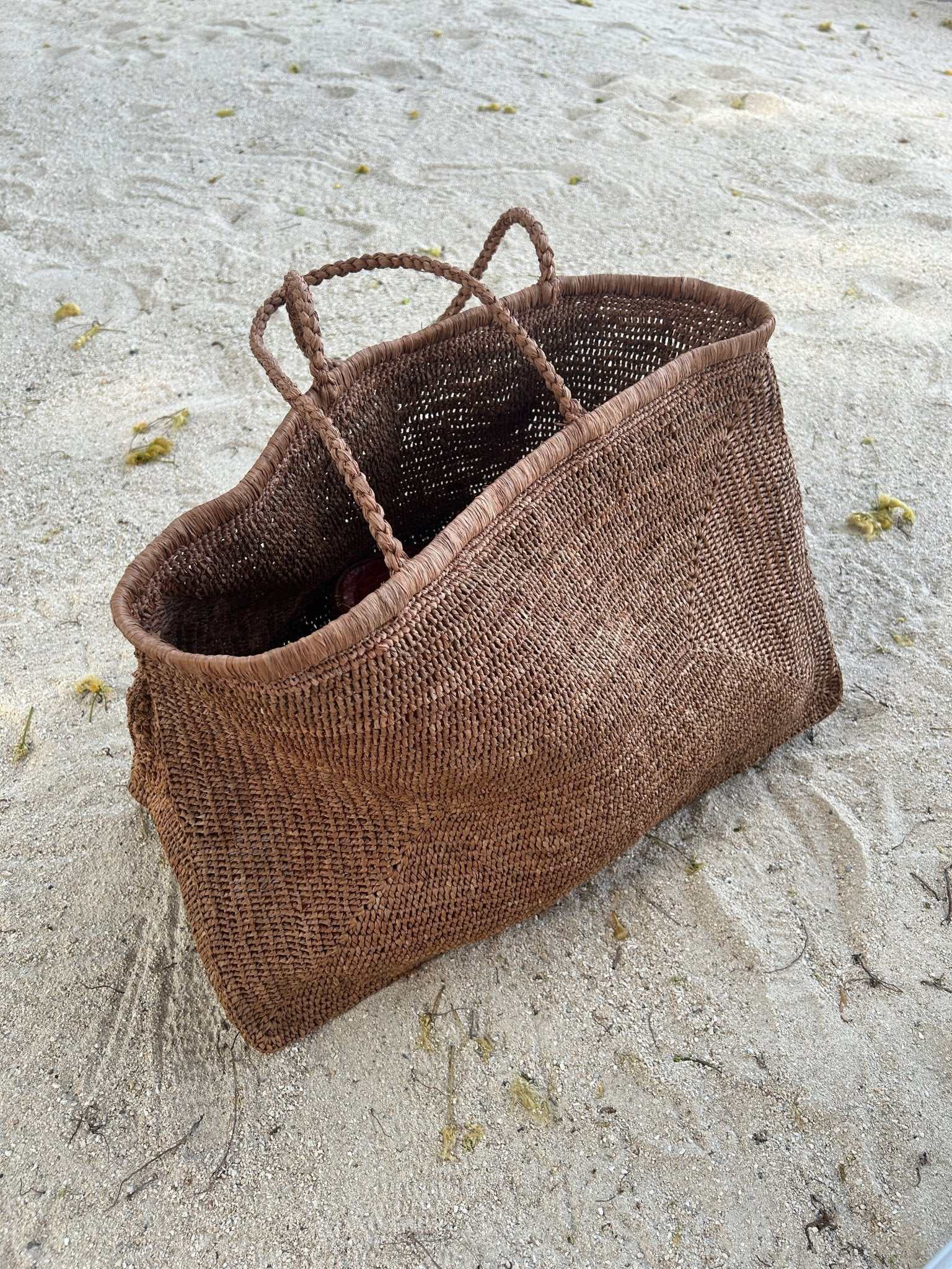 Caramel brown woven raffia tote bag with twin rope handles and roomy shape.