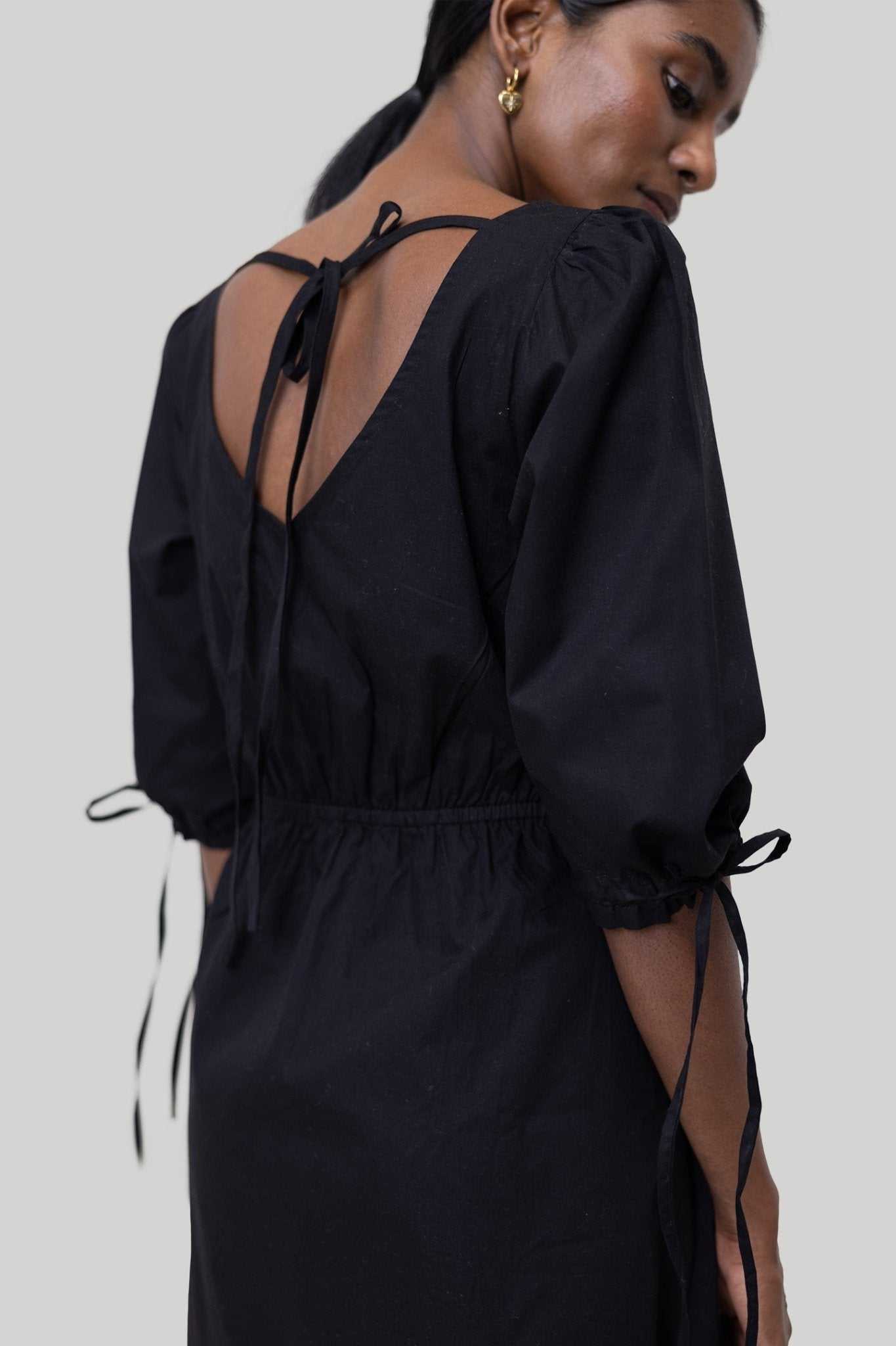 Black back view: open V-back with long bow ties and gathered waist