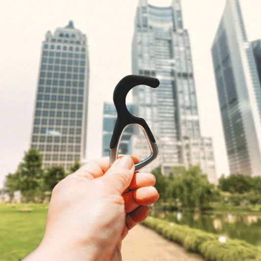 Black silicone no-touch keychain tool, held in hand with metal key ring