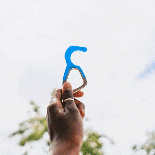 Blue silicone no-touch keychain tool raised outdoors, metal ring visible