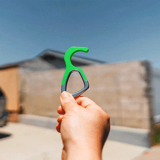 Green silicone no-touch keychain tool with metal ring in a hand grip