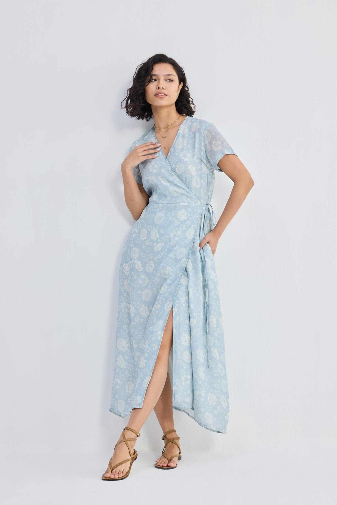 Side view of light-blue floral wrap maxi dress with flowing hem and waist sash