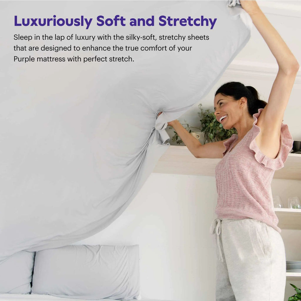 Stretch sheets in light grey, lifted fitted corner showing deep pocket fit