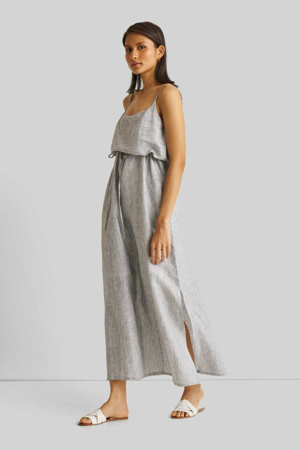 Side view: pinstriped linen maxi dress with slit and flowing, gathered skirt