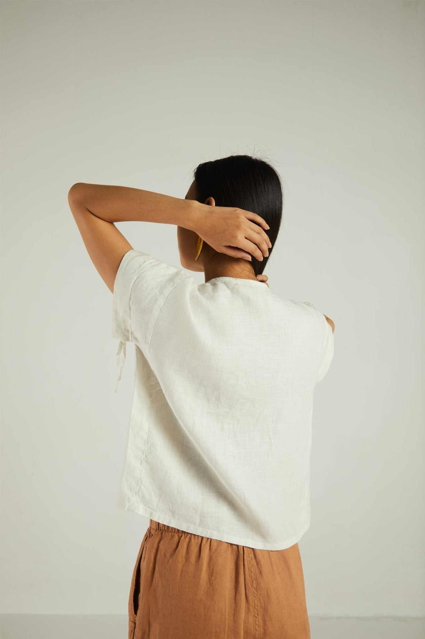Back view: shell off-white short-sleeve shirt with loose fit and tied sleeve hems